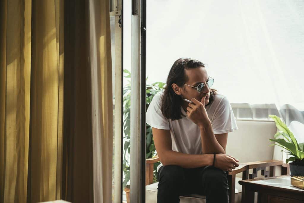 man sitting smoking balcony