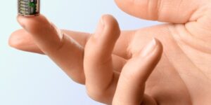 A Tiny Cubical Device Is Balanced On A Fingertip.jpg