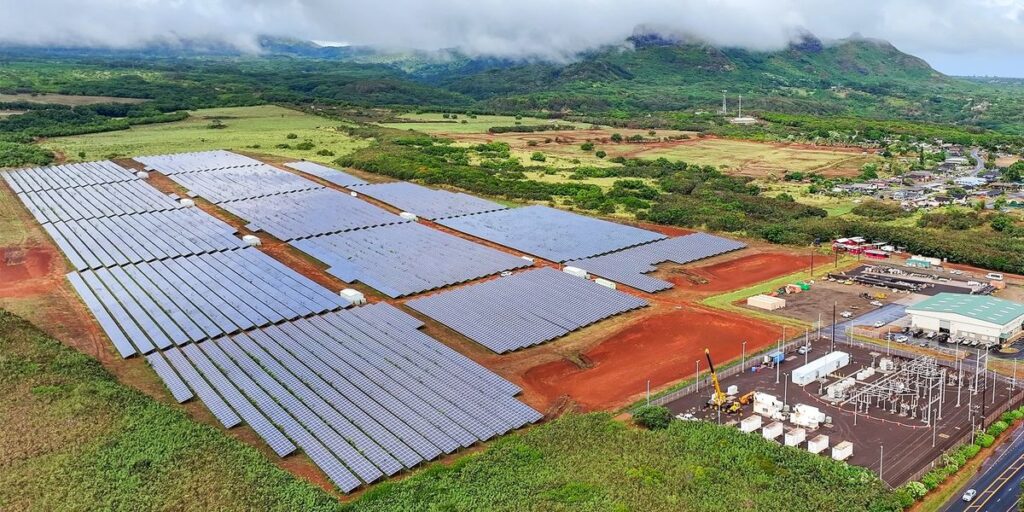 Multiple Solar Panel Arrays Next To An Electrical Substation In A Lush Green Environment.jpg