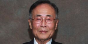 1708694289 Portrait Of A Man Wearing A Suit And Glasses Looking At The Camera Against A Gray Background.jpg