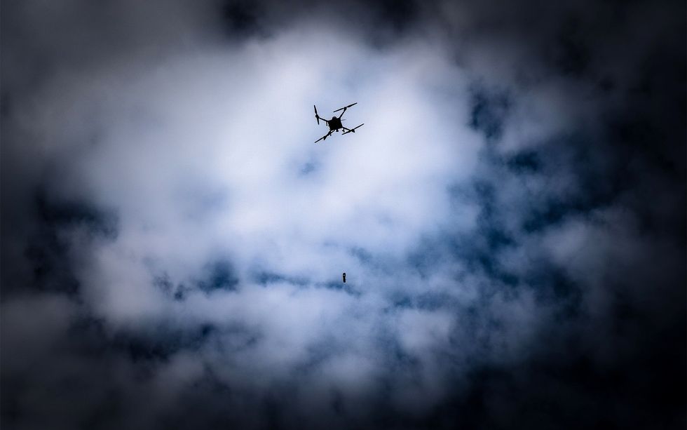 a dark cloudy sky behind the silhouette of a drone and an anti tank grenade