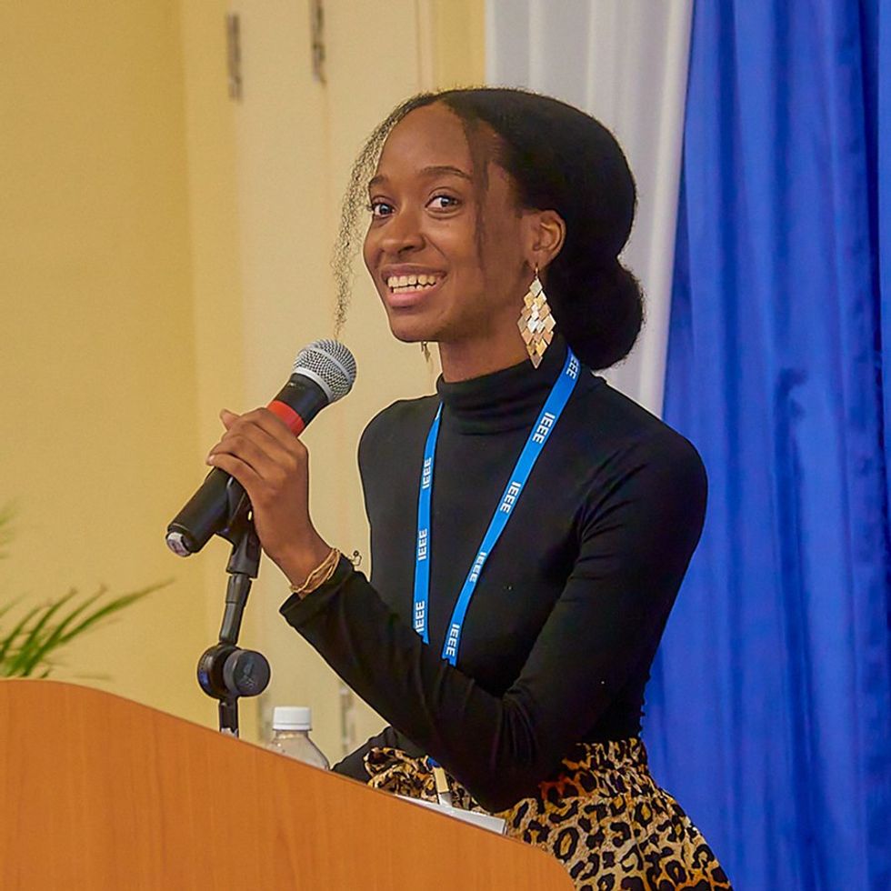 a smiling young woman smiles while holding a microphone