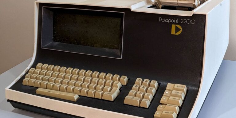 brown and beige box with curved end in front with a keyboard and screen and two pieces sticking out on top right side